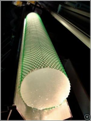 A one-meter long piece of ice core illuminated with a light. The green netting on the core is used to help hold the ice together in case it spontaneously fractures.